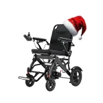 A black electric wheelchair with a festive red Santa hat placed on the backrest, set against a plain white background for a cheerful holiday look.